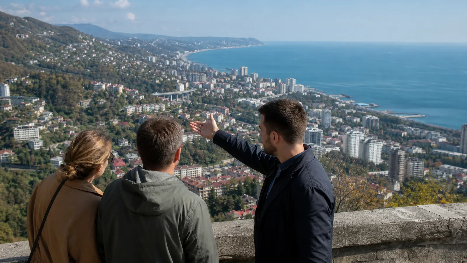 Пара и консультант смотрят на панораму Большого Сочи, выбирая район для постоянной жизни